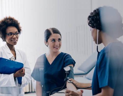 Nurse educator instructing two nursing students during class